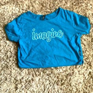 Cropped teal tshirt with the word imagine written on it